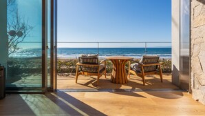 Een kamer met een glazen deur die uitkomt op een balkon met uitzicht op zee.