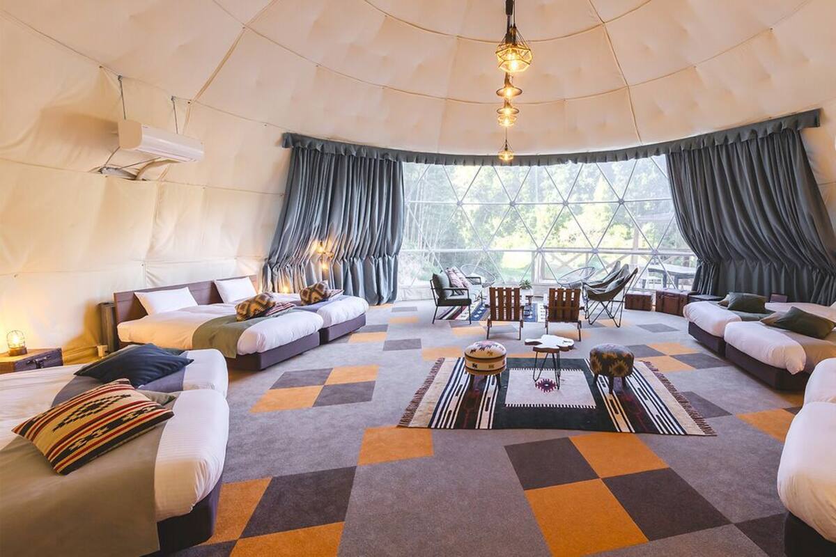 Una habitación amplia con un gran ventanal, un conjunto de sofá, una mesita de centro y una lámpara colgante.