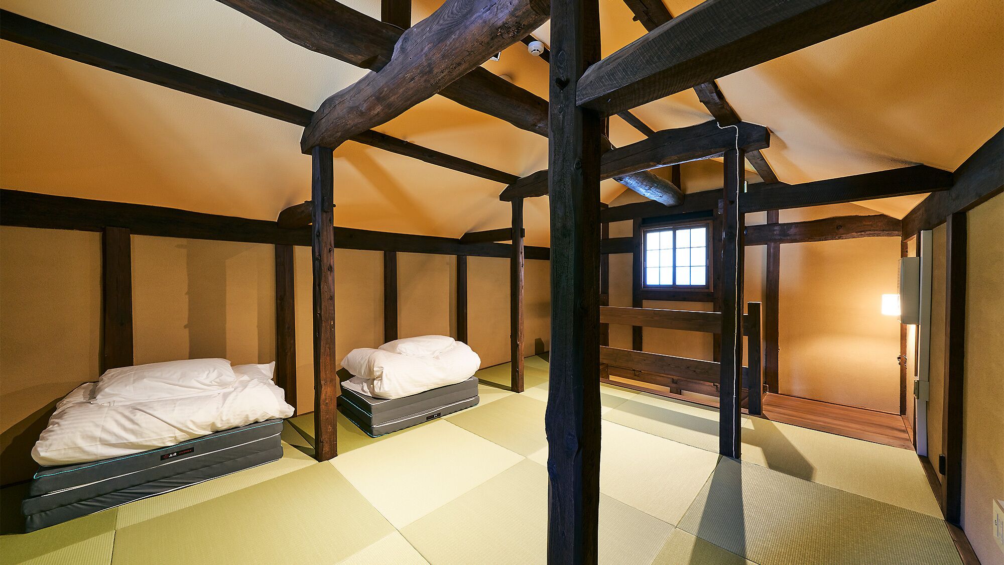 Una habitación tradicional japonesa con suelo de tatami, vigas de madera y techo bajo.
