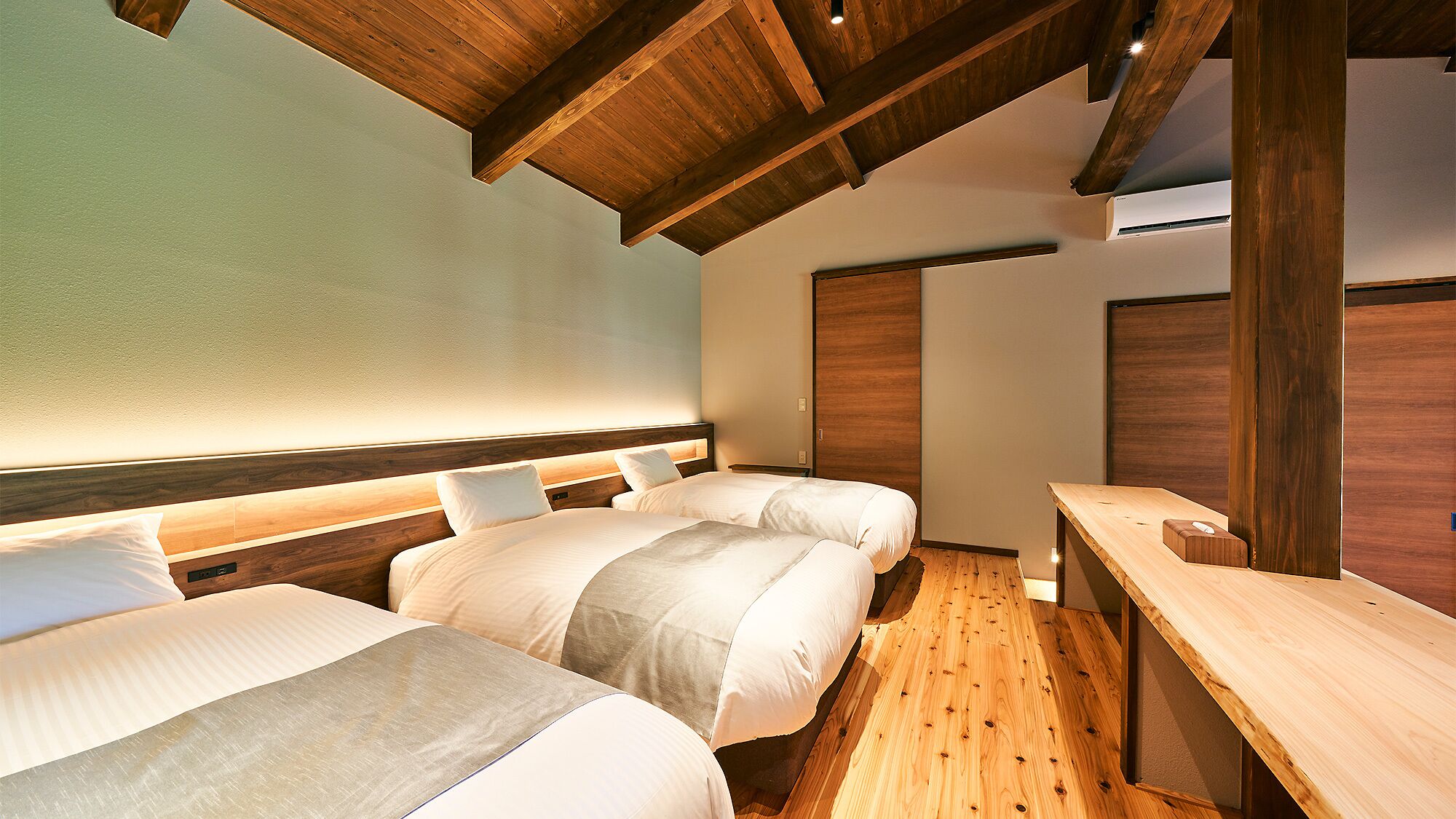 Habitación de hotel con dos camas, vigas de madera, una mesa de madera y un armario.