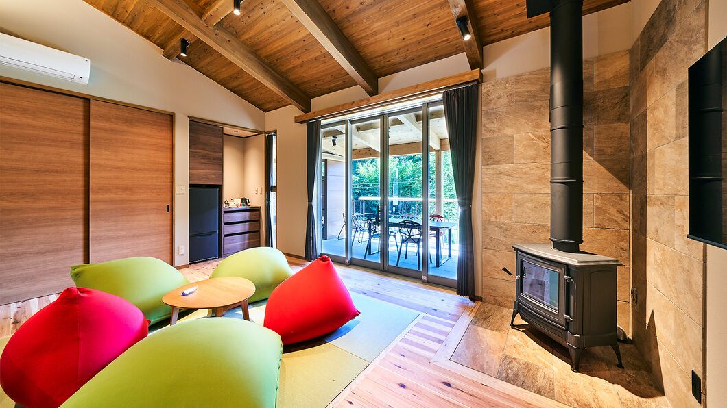 Un interior moderno con techo de madera, chimenea y vista a un espacio exterior a través de amplios ventanales.