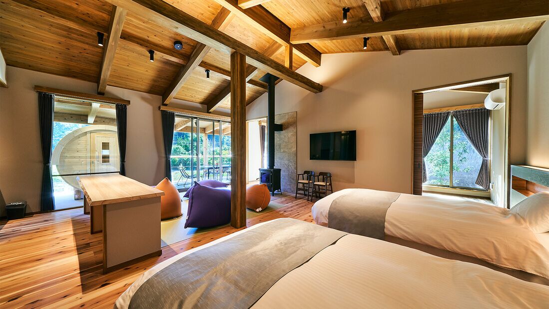 Un dormitorio moderno con vigas de madera, dos camas, un televisor y vistas al exterior.