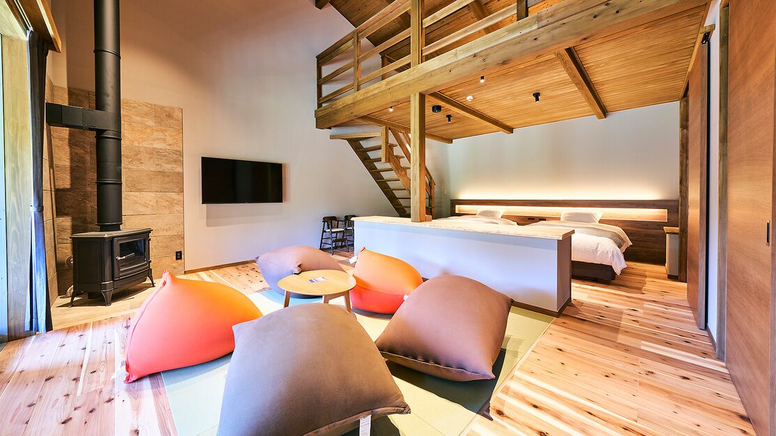 Un interior moderno con suelo de madera, un sofá, una cama, un televisor y una chimenea.