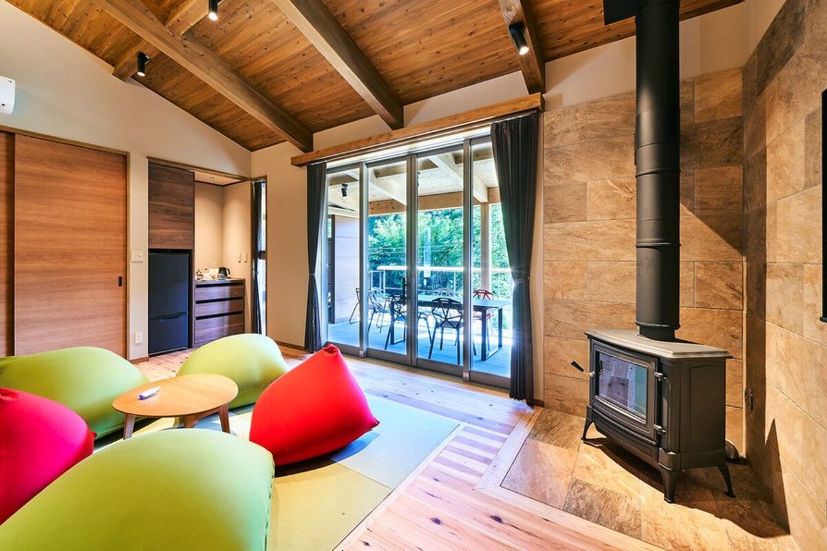 Un interior moderno con techo de madera, chimenea y vista a un espacio exterior a través de amplios ventanales.