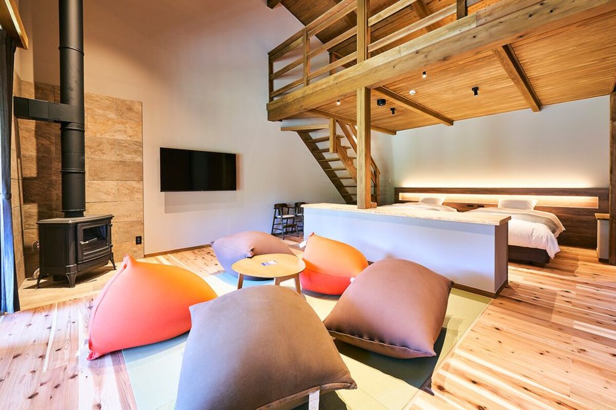 A modern interior with a wooden floor, a sofa, a bed, a TV, and a fireplace.