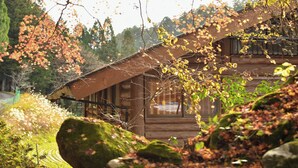 Une cabane rustique avec un toit en pente, de grandes fenêtres et des fondations en pierre.