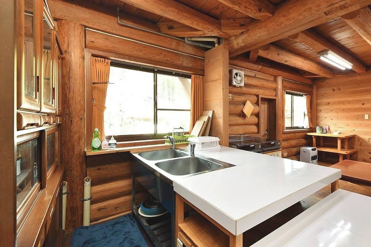 A cabin-style kitchen with wooden walls, a central island, and a window.