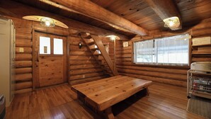 L’intérieur d’un chalet en bois, avec un banc en bois, un escalier et une fenêtre donnant sur un paysage.