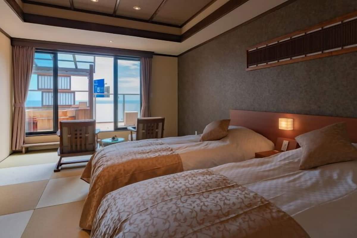 Quarto de hotel com uma cama grande, uma escrivaninha e vista para o mar.