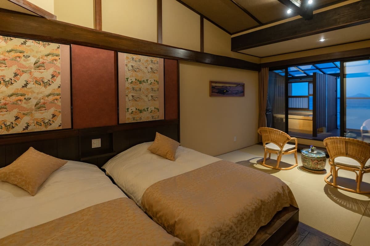 Quarto de hotel com duas camas, varanda com vista e decoração tradicional.