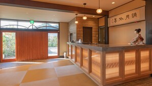 Un'area di accoglienza con un bancone in legno, un elemento decorativo tradizionale giapponese e un cartello con caratteri giapponesi.