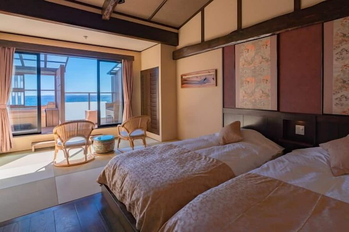 Quarto de hotel com duas camas, uma janela ampla com vista e decoração japonesa tradicional.