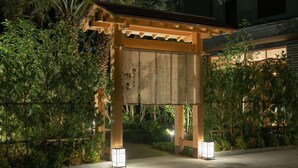 Un tradizionale torii giapponese con struttura in legno e una galleria coperta, circondato da vegetazione lussureggiante.