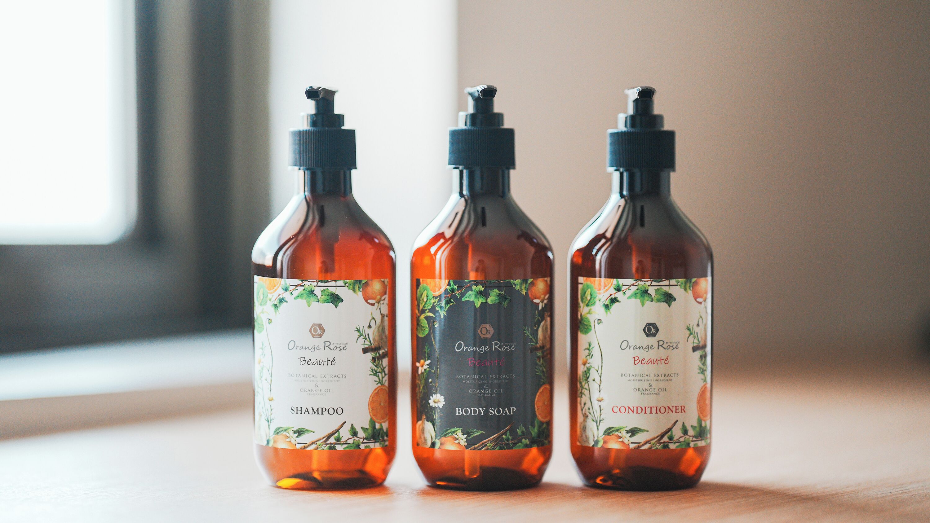 Three bottles of Orange Rose products on a wooden surface.