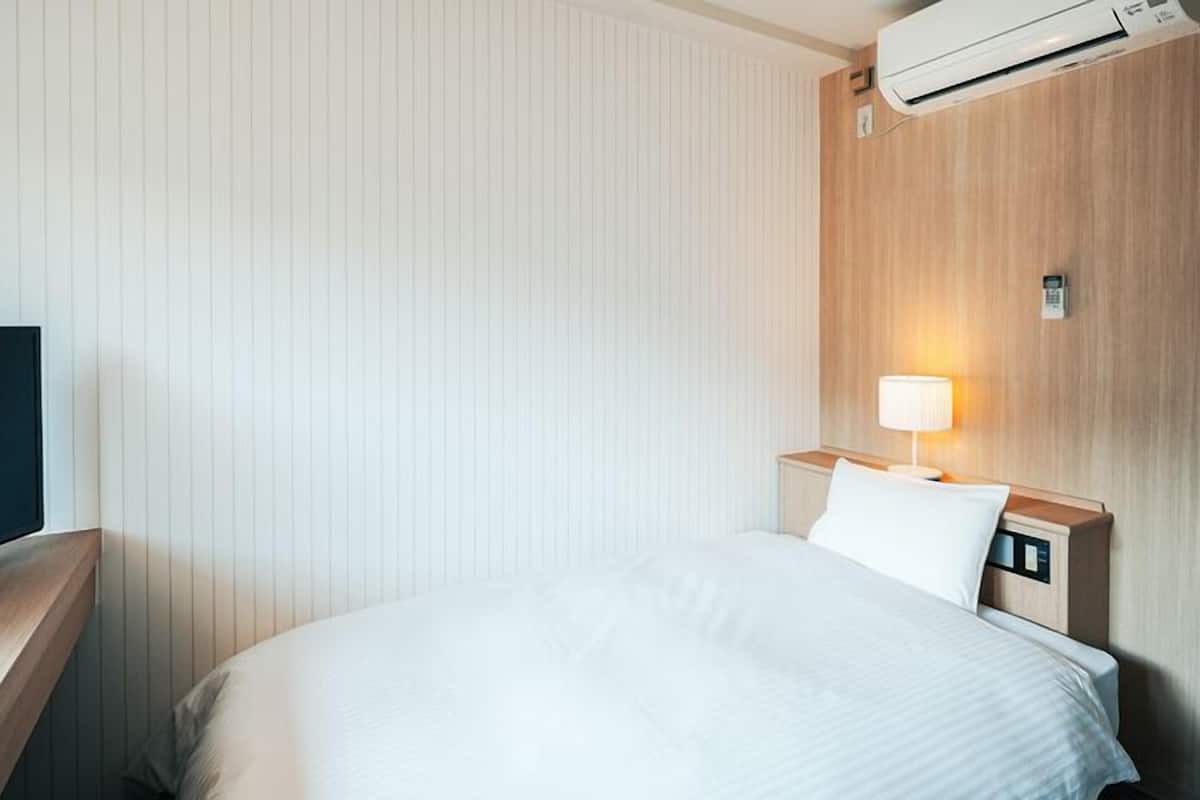 Ein Hotelzimmer mit Bett, Fernseher, Nachttischlampe und Klimaanlage.