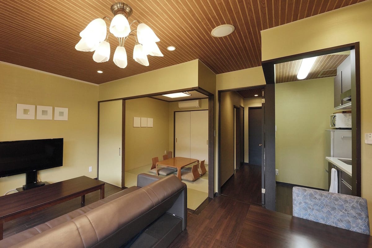 Un salon moderne doté d’un téléviseur à écran plat, d’un plafond en bois, d’un canapé et d’un coin repas avec des chaises.