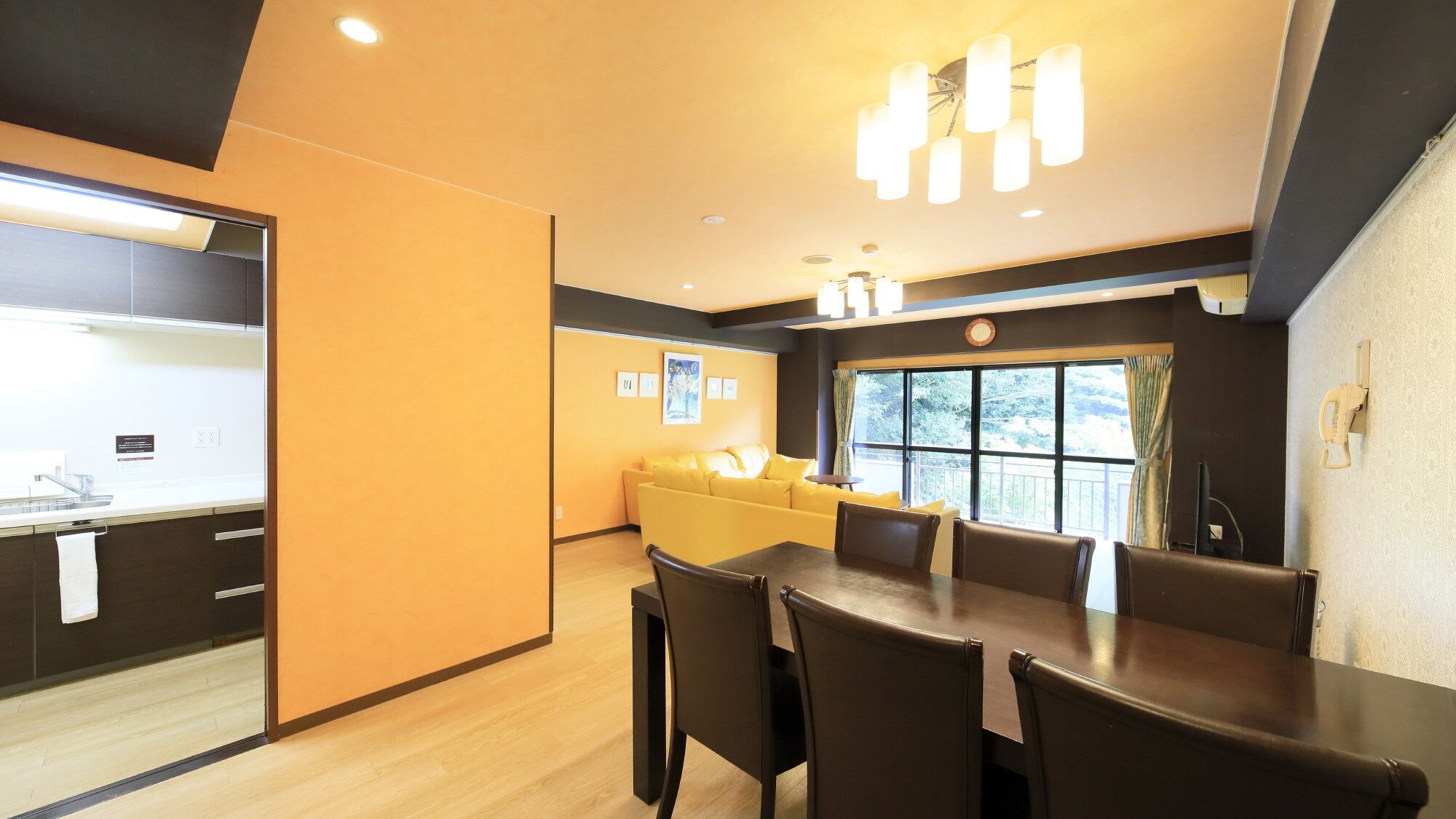 A modern hotel room with a dining area, a sofa, and a large window.