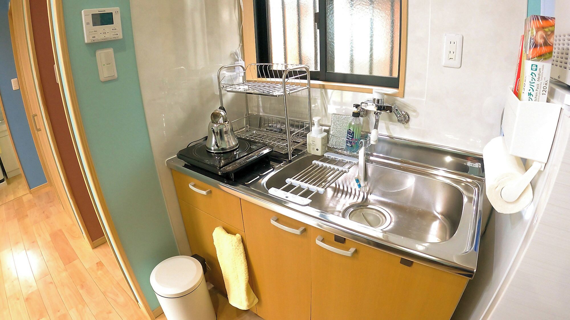 A compact kitchen with a sink, a stove, a microwave, and a small trash bin.