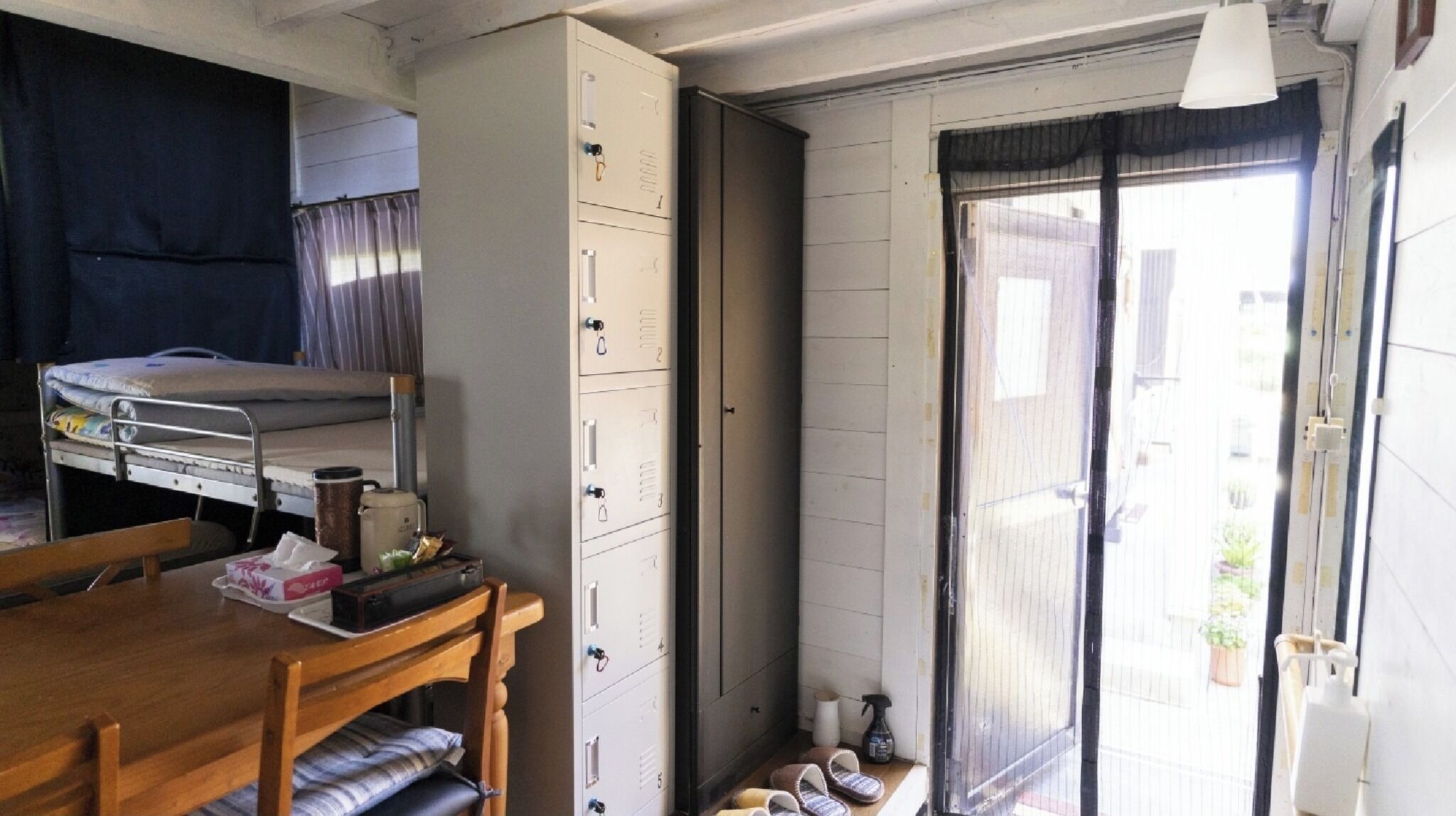 A compact room with a bunk bed, a wooden table, a cabinet, and a sliding door leading to an outdoor area.