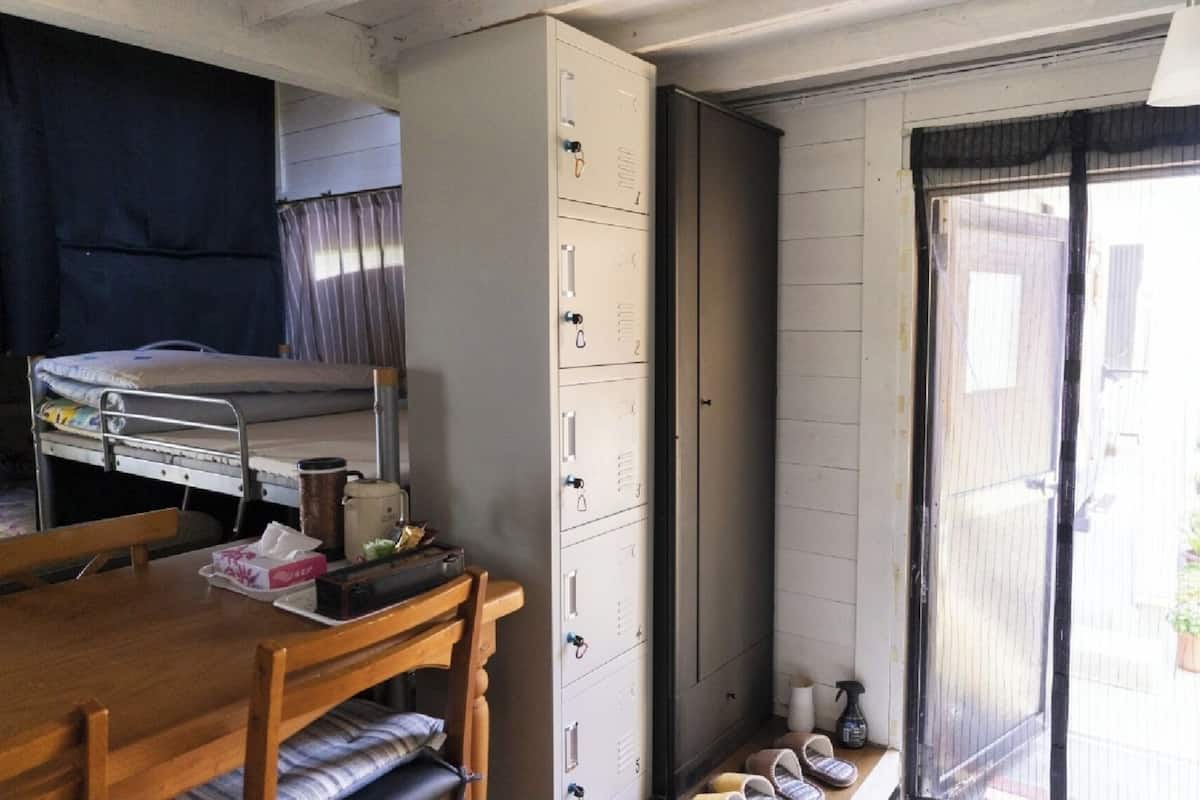 A compact room with a bunk bed, a wooden table, a cabinet, and a sliding door leading to an outdoor area.