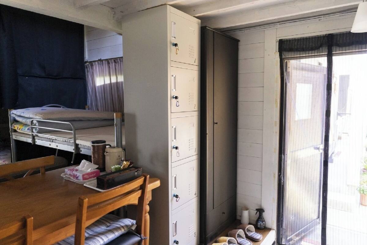 A compact room with a bunk bed, a wooden table, a cabinet, and a sliding door leading to an outdoor area.