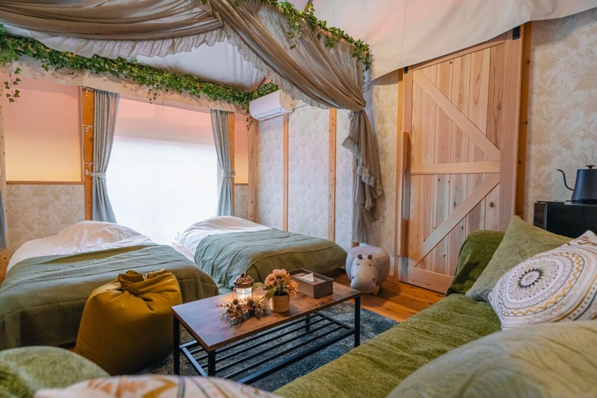 A cozy room with two beds, a small table with a vase, and a wooden wardrobe.