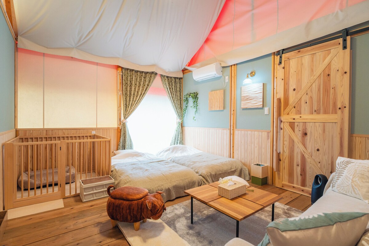 A cozy room with two beds, a wooden crib, a small table, and a sofa.