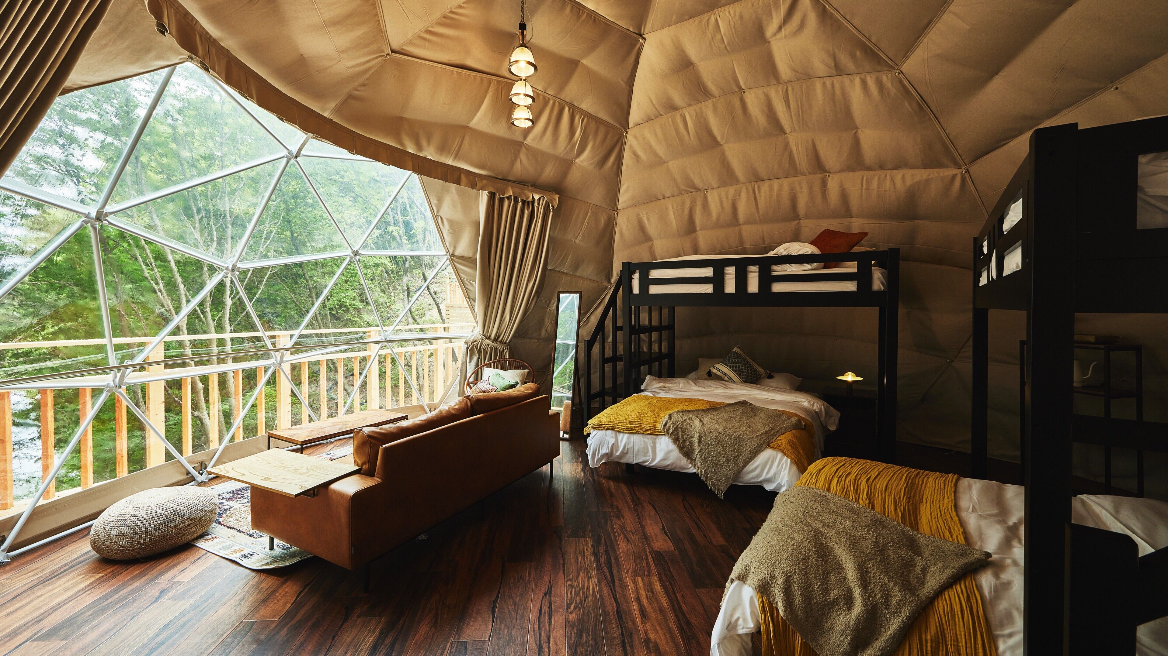 Una habitación con dosel, con literas, un sofá y vistas al bosque.