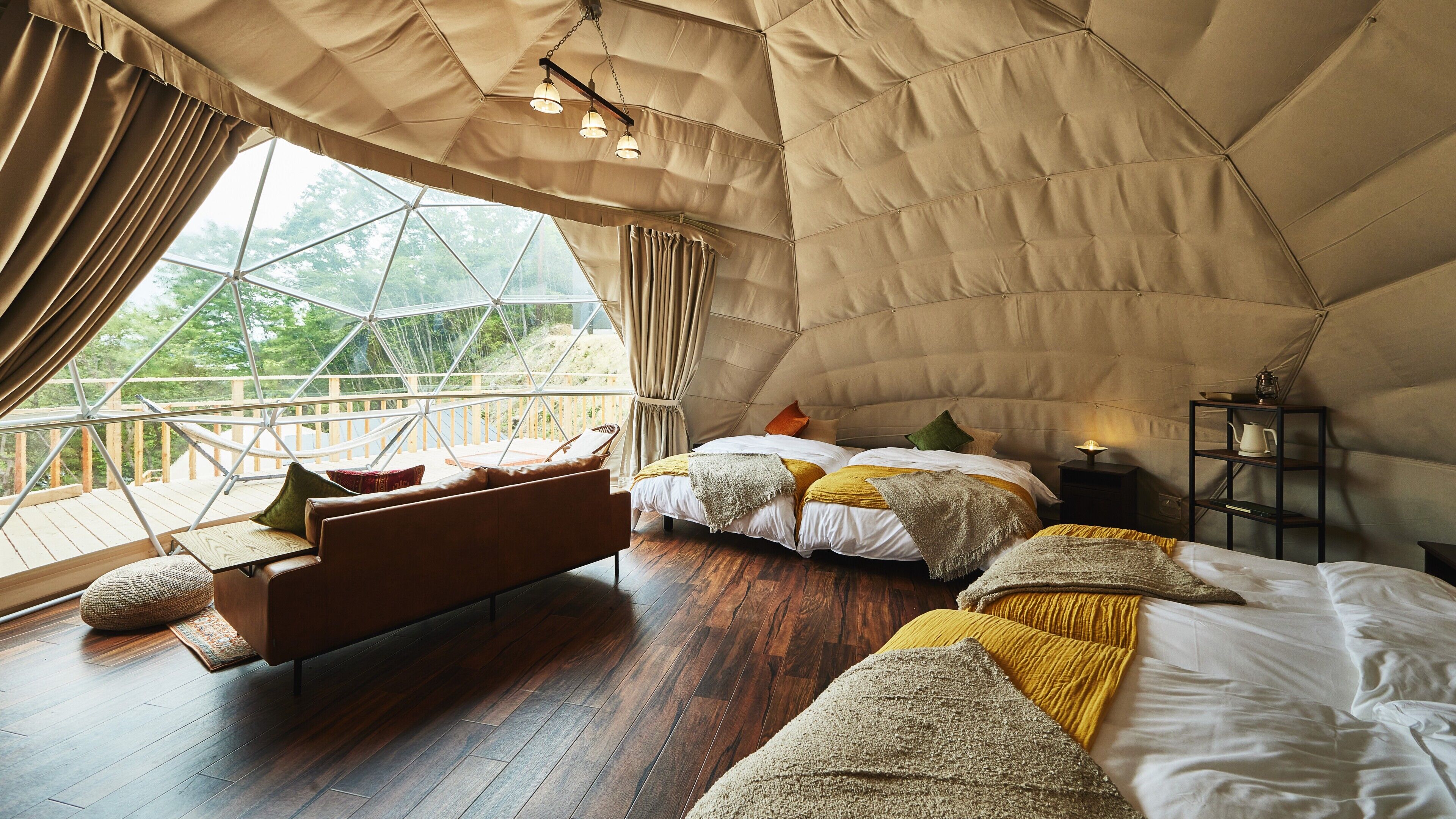 Una habitación tipo tienda de campaña con cama, zona de estar y vistas a través de un gran ventanal.