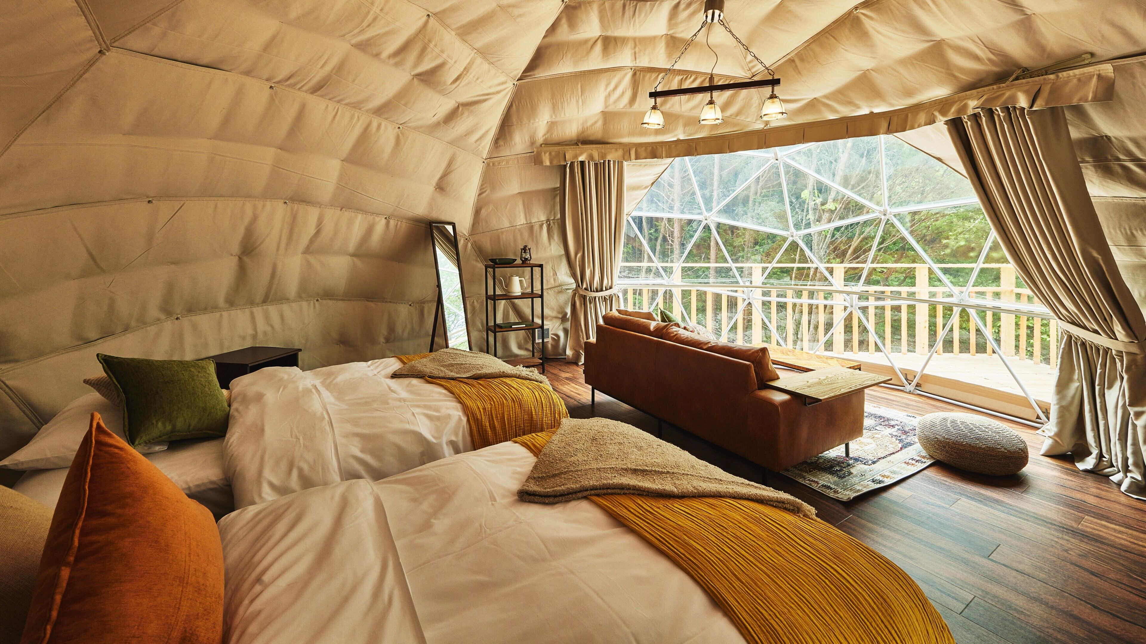 Alojamiento tipo tienda con cama, sofá y vistas al exterior.