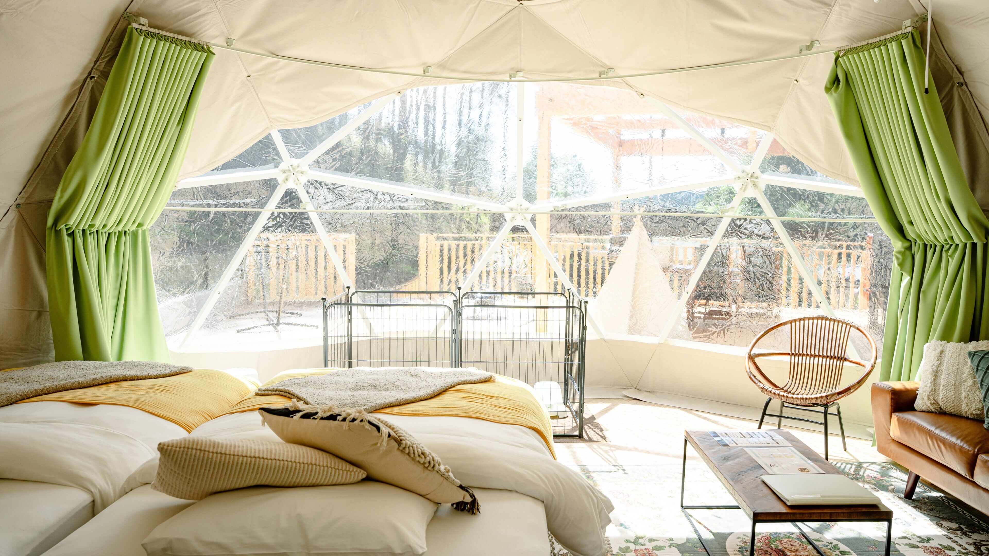 Una habitación con carpa, una cama, una silla, una mesa y vistas a un bosque.
