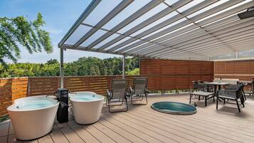 An outdoor deck with a pergola, seating, a hot tub, and a pool.