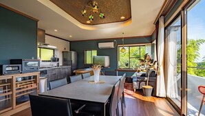 A modern kitchen with a dining area, large windows, and a view of greenery. - Maigre Yebisu (Sado)
