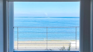 Uma janela com vista para o oceano e uma praia.