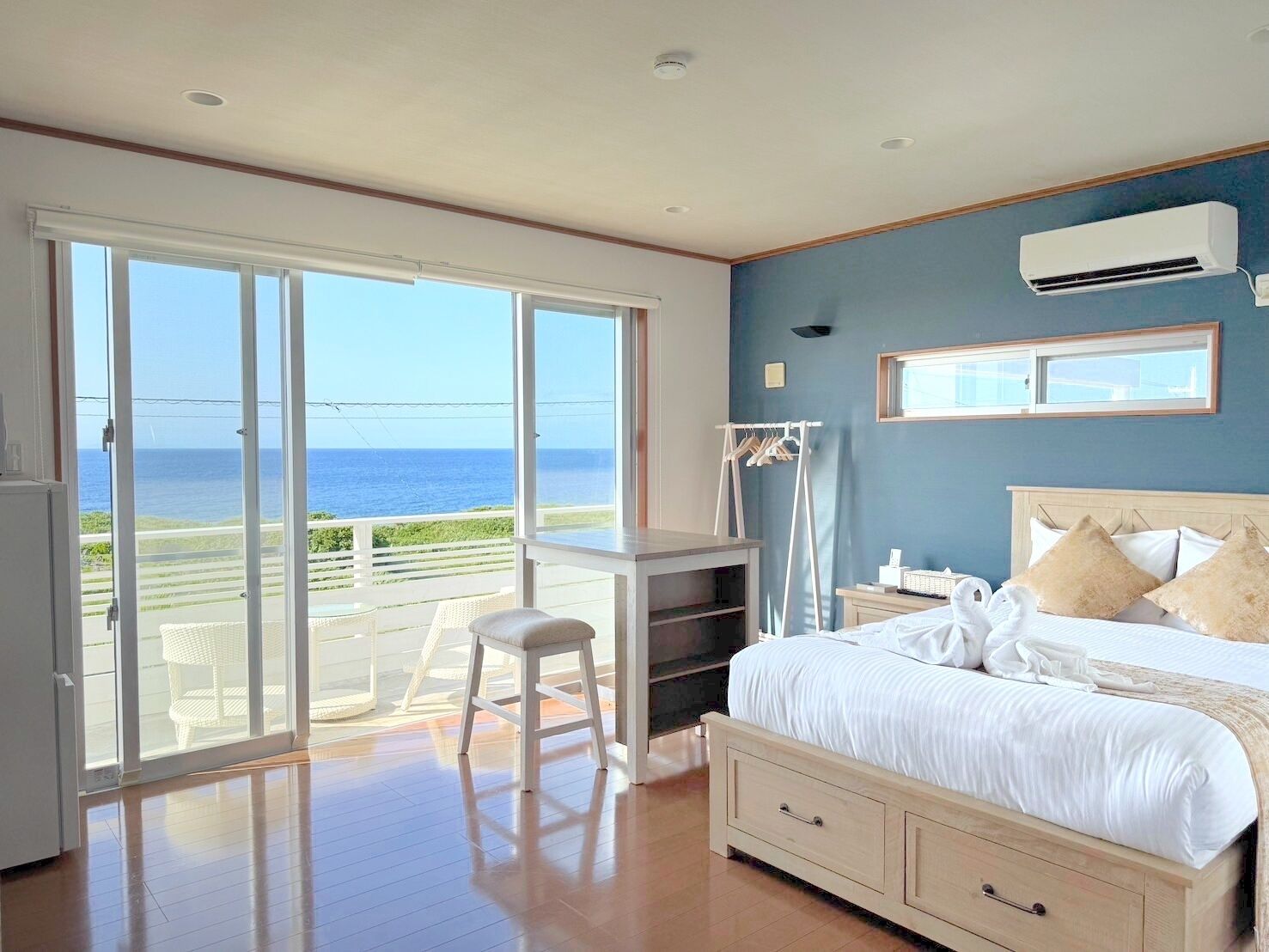 Quarto com cama, escrivaninha e cadeira, varanda com vista para o mar e ar condicionado.