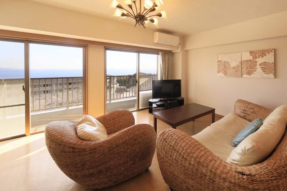 Ein Wohnzimmer mit Rattanmöbeln, einem Fernseher und einem Balkon mit Blick.