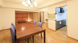 A dining area with a wooden table and chairs, a kitchen with a sink and cabinets, and a hallway leading to another room. - Point Vacation Izu Kogen (Ito)