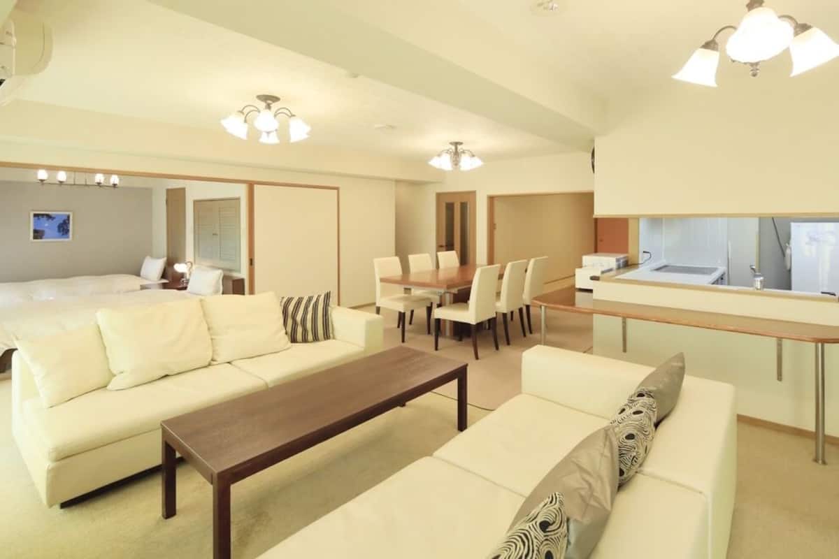 Ein Hotelzimmer mit einem Bett, zwei Sofas, einem Esstisch mit Stühlen, einer Küchenzeile und einem Badezimmer.