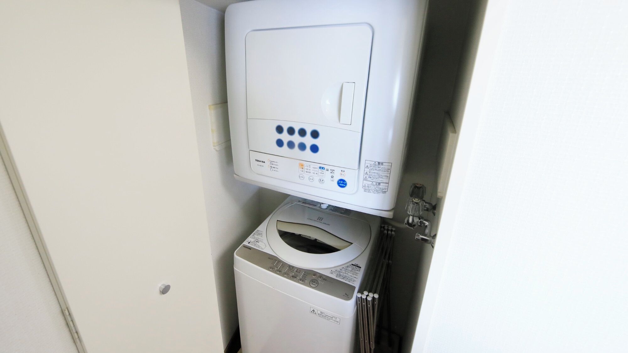 A washing machine and dryer unit in a small, enclosed space with a door.