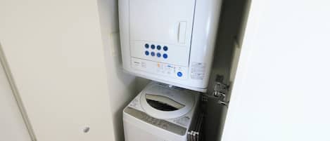 A washing machine and dryer unit in a small, enclosed space with a door.