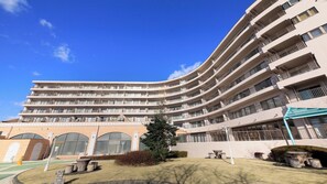 Un hotel de varios pisos con fachada curva, balcones y un patio con zonas de estar.