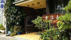 A building with a brick facade, a covered entrance, and potted plants. - Nakahamaya (Izu)