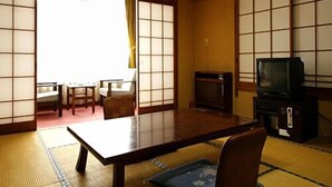 A traditional Japanese room with tatami flooring, a low table, a television, and sliding doors. - Nakahamaya (Izu)