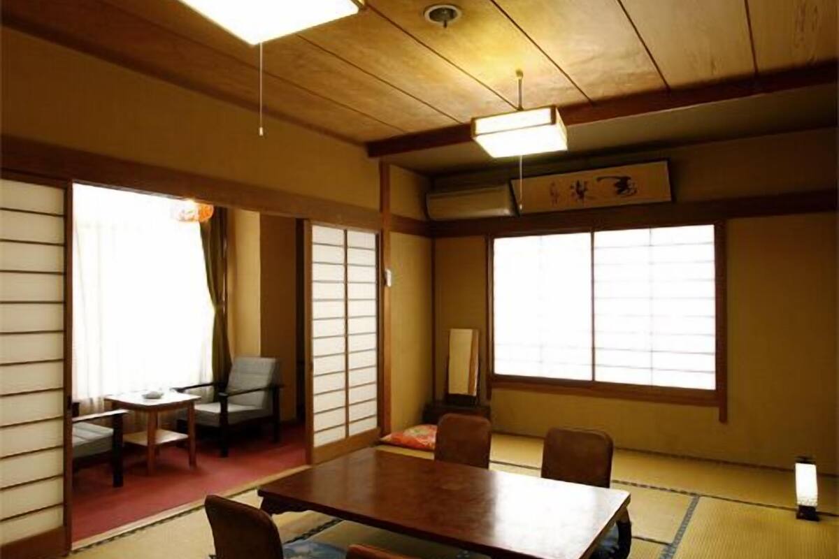 A traditional Japanese room with tatami flooring, a low table, and sliding doors.