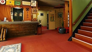 A hotel lobby with a reception desk, a staircase, and a patterned carpet. - Nakahamaya (Izu)