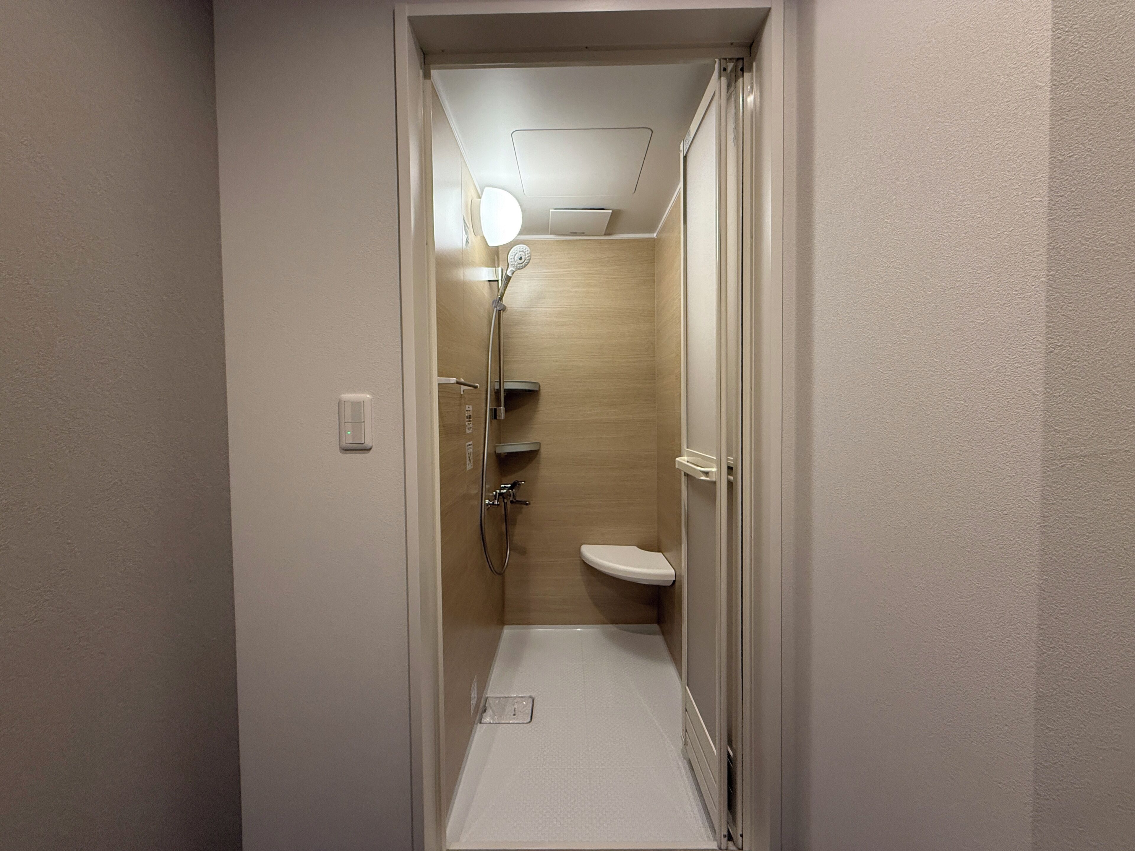 Une petite salle de bain comprenant une douche, des toilettes et un luminaire au plafond.