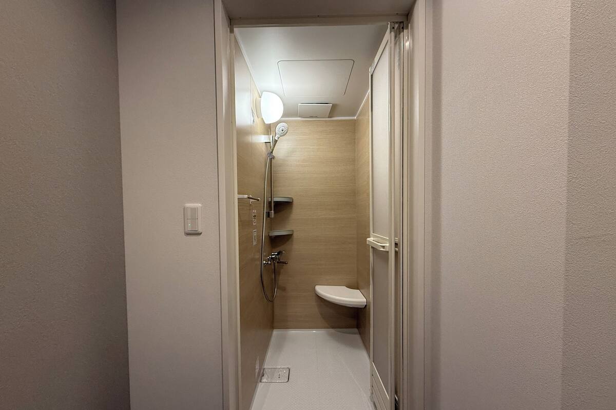 Une petite salle de bain comprenant une douche, des toilettes et un luminaire au plafond.