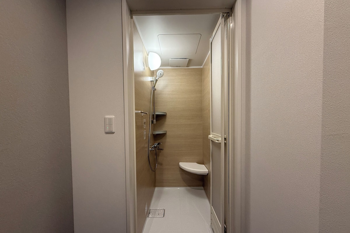 Un baño pequeño con ducha, inodoro y una lámpara en el techo.