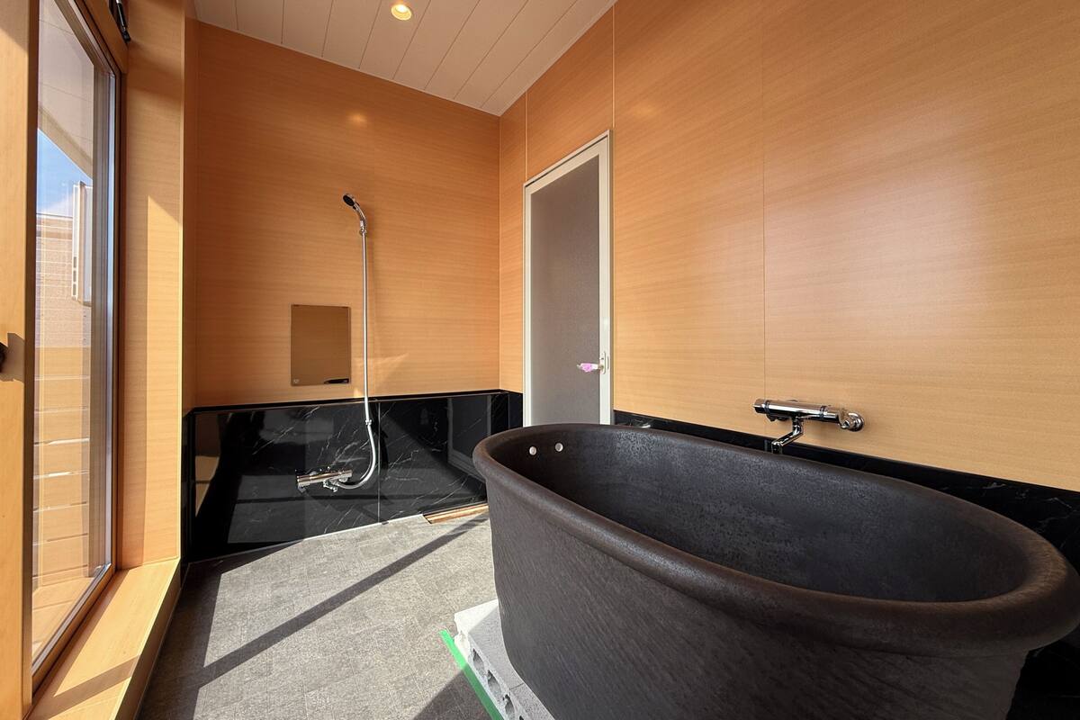 Une salle de bain moderne dotée d’une grande baignoire, d’une douche et d’un meuble-lavabo avec un miroir.