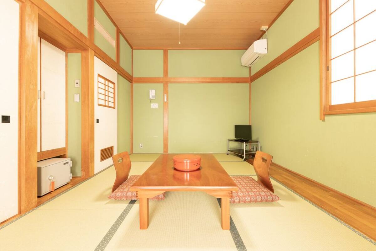 Une pièce de style japonais traditionnel, avec un sol recouvert de tatamis, une table en bois et des portes coulissantes.